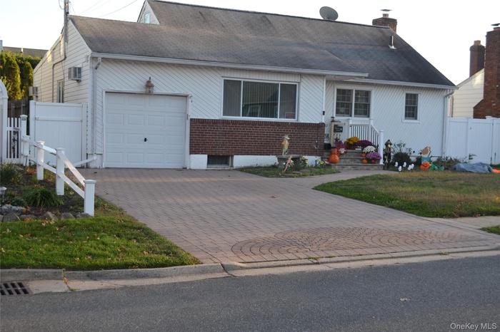 View of front of property with decorative driveway, a garage, a chimney, a shingled roof, and brick siding