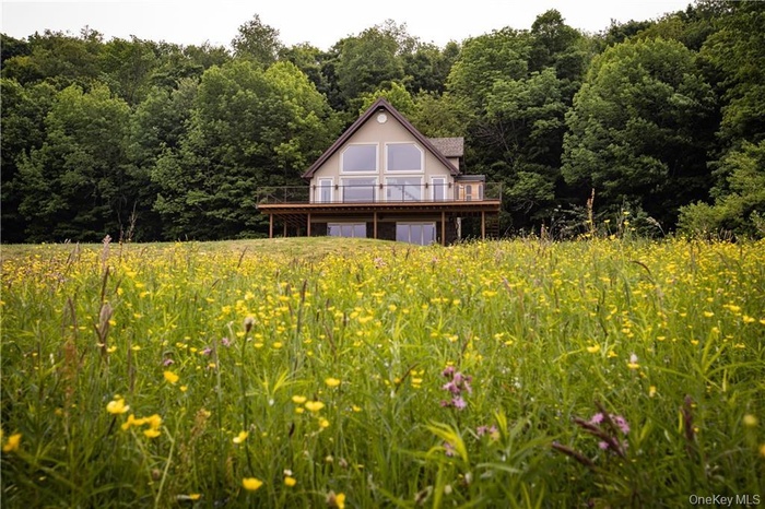 Back of house featuring a deck and a wooded view