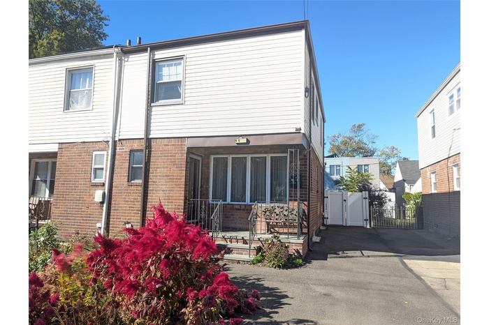 Back of property featuring a gate, brick siding, a sunroom, and a wooden deck