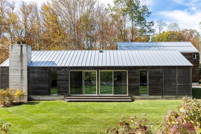Back of property featuring a yard, a standing seam roof, a metal roof, and a chimney