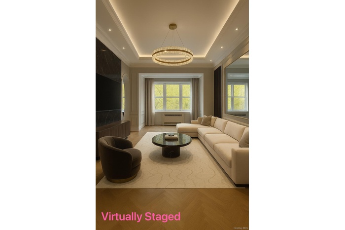 Living room with a tray ceiling, radiator, arched walkways, ornamental molding, and recessed lighting