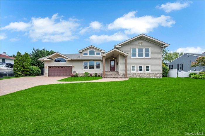 View of front of property featuring decorative driveway, stone siding, and an attached garage