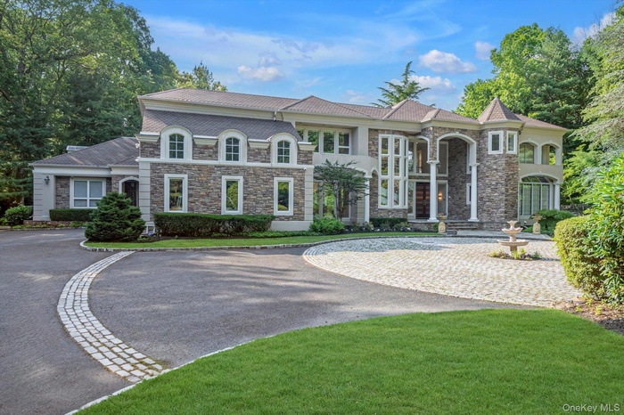 View of front of property with stone siding, curved driveway, and a front yard