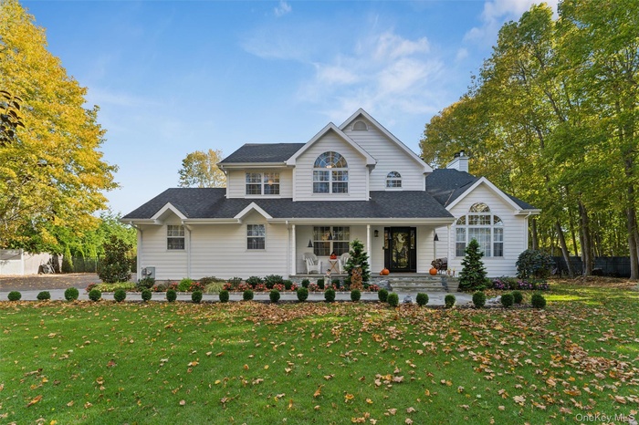 View of front of home with a porch, roof with shingles, and a chimney