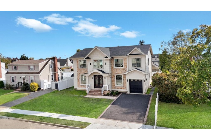 View of front of home with stone siding, driveway, a residential view, and a garage