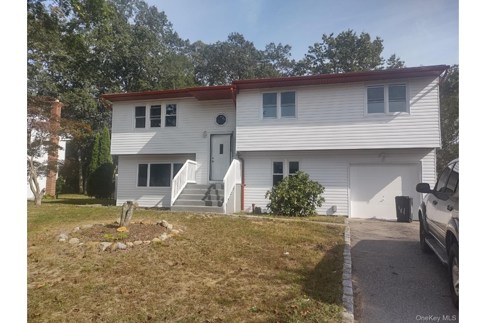 Split foyer home with an attached garage, a front lawn, and driveway