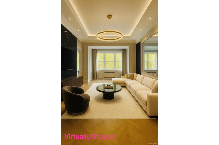 Living room with a tray ceiling, arched walkways, radiator heating unit, ornamental molding, and recessed lighting