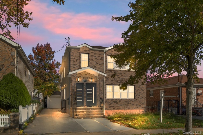 View of front of house with brick siding, driveway, and an outdoor structure