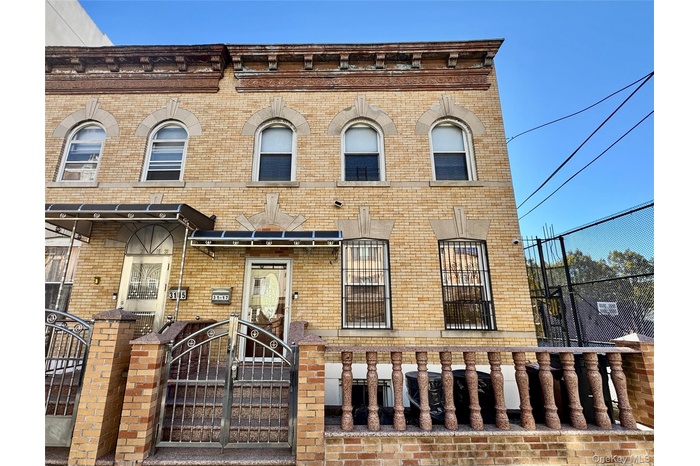 Italianate house featuring brick siding, a fenced front yard, and a gate