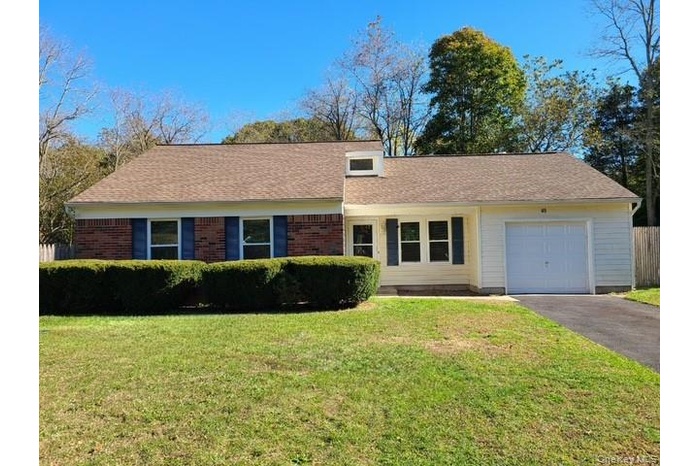 Single story home featuring asphalt driveway, a garage, a shingled roof, and brick siding
