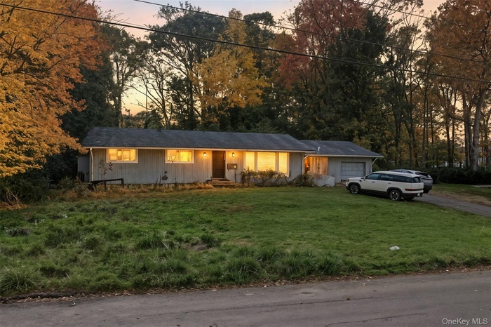 Ranch-style house with an attached garage, driveway, a lawn, and board and batten siding