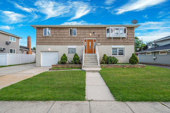 Bi-level home featuring concrete driveway, a garage, and stucco siding