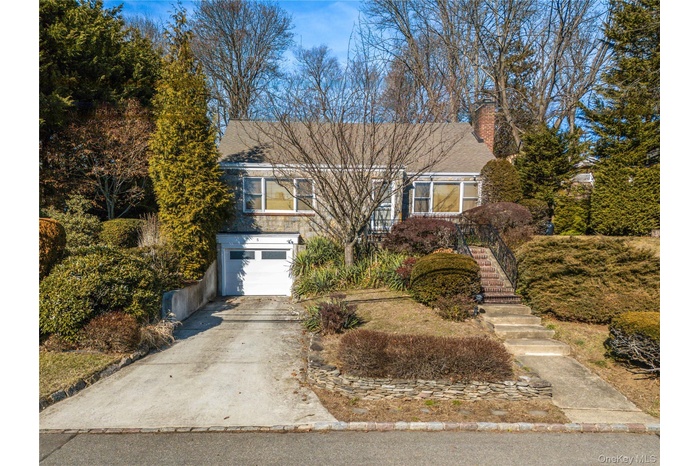 View of front of property featuring driveway, stairway, an attached garage, and a chimney