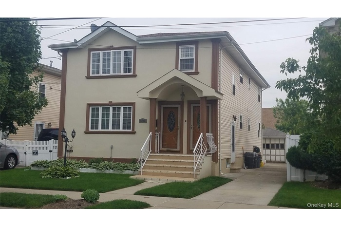 Traditional-style home featuring stucco siding, an outbuilding, and a detached garage