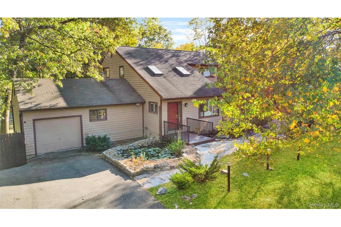 View of front of home with a garage, asphalt driveway, and a shingled roof