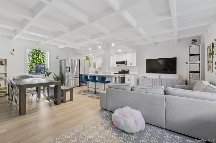 Living area featuring beamed ceiling, coffered ceiling, and light wood-style flooring