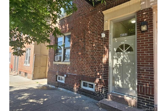 View of exterior entry featuring brick siding, cooling unit, and a patio area