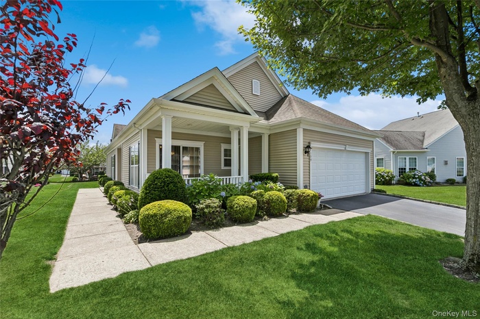 View of front of house featuring a garage, a porch, a front yard, and driveway