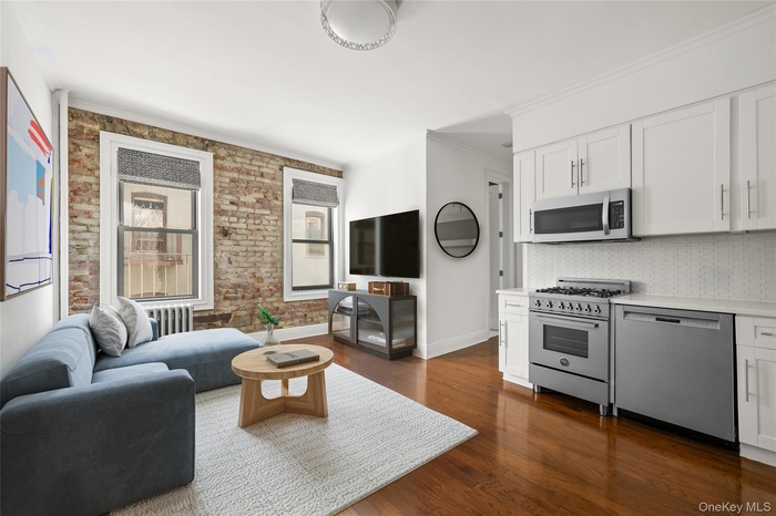 Living area featuring ornamental molding, dark wood-type flooring, radiator heating unit, and brick wall