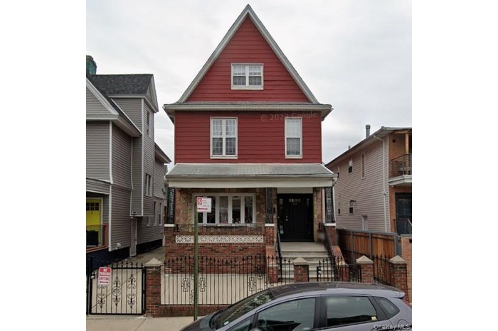 Traditional style home with a gate, a fenced front yard, covered porch, and stone siding