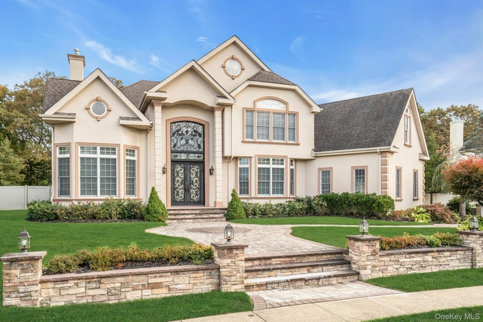 View of front of home with stucco siding, a shingled roof, and a chimney