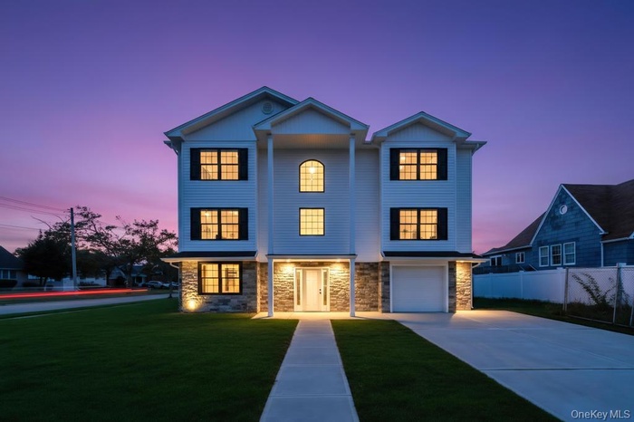 View of front of house featuring driveway, stone siding, and a garage