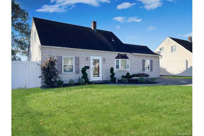 Cape cod-style house featuring a chimney and roof with shingles