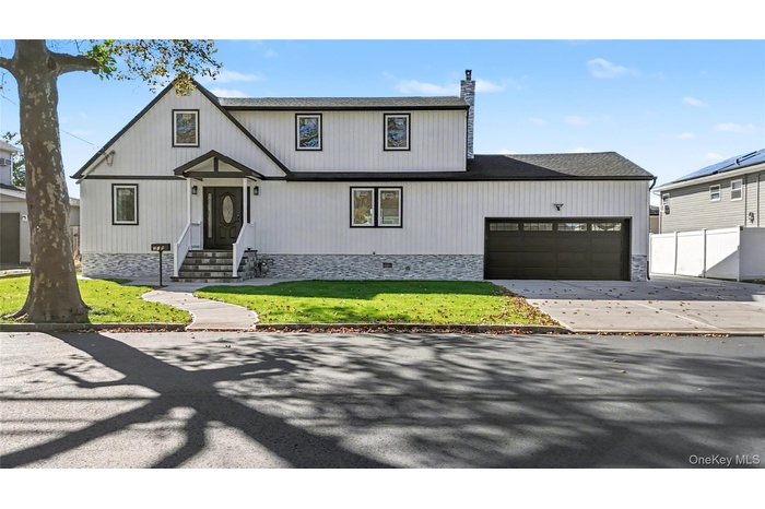 Modern farmhouse featuring driveway, a shingled roof, a garage, and a chimney