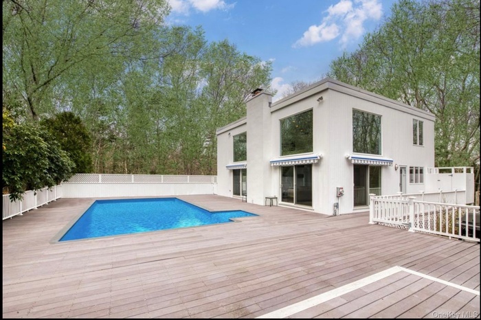 View of swimming pool featuring a wooden deck and a fenced backyard