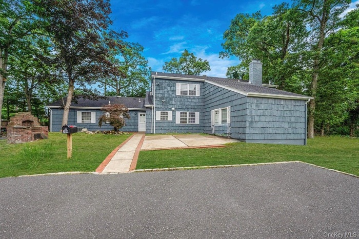 View of front of property with a chimney, a patio area, a front lawn, and roof with shingles