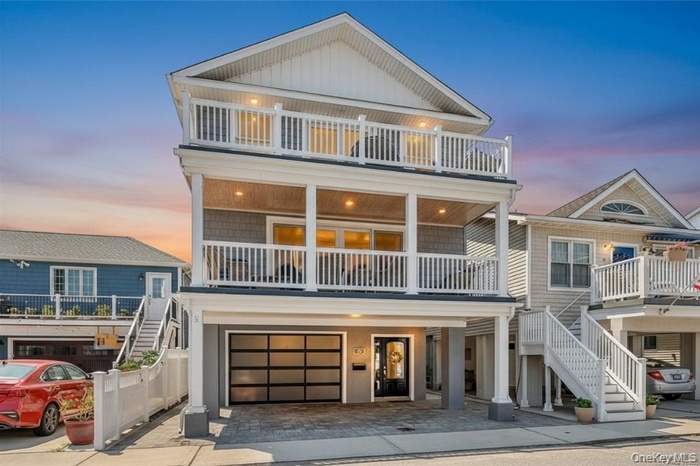 View of front facade featuring stairway, decorative driveway, an attached garage, and a balcony