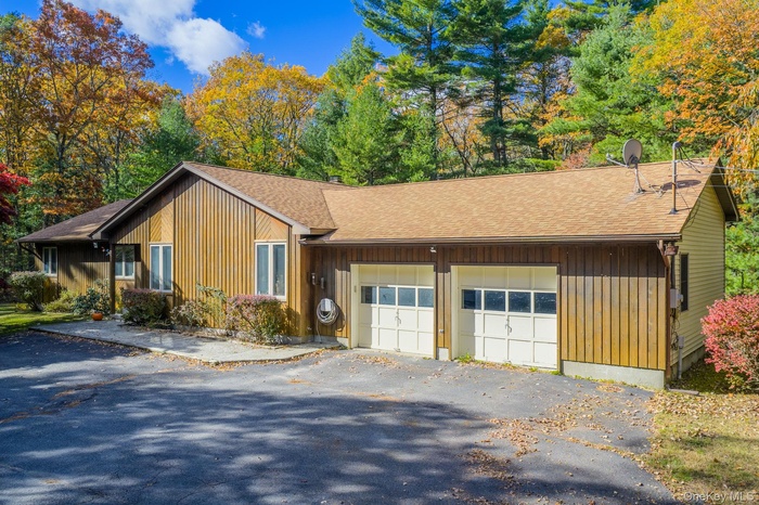 View of front facade featuring roof with shingles, an attached garage, and driveway