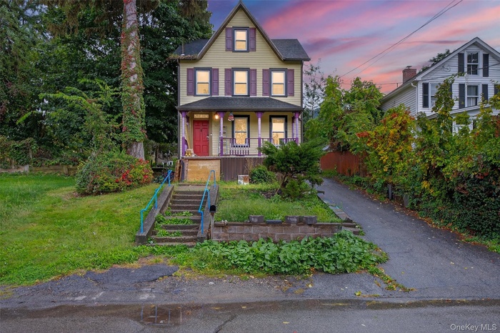 Victorian home with a porch, a front yard, driveway, and stairs