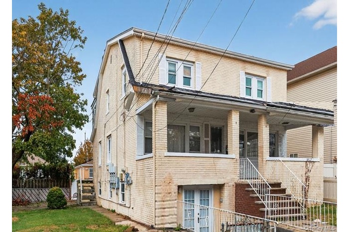 Back of house featuring brick siding, stairs, and covered porch