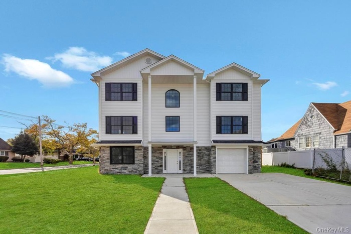 View of front of home with stone siding, concrete driveway, and a garage