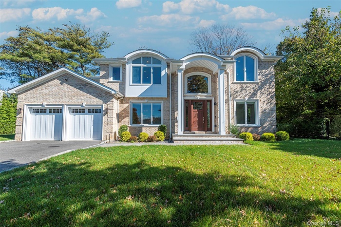 View of front of property with a front lawn, driveway, a garage, and brick siding
