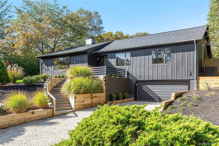 Mid-century home featuring stairs, board and batten siding, a shingled roof, and a chimney