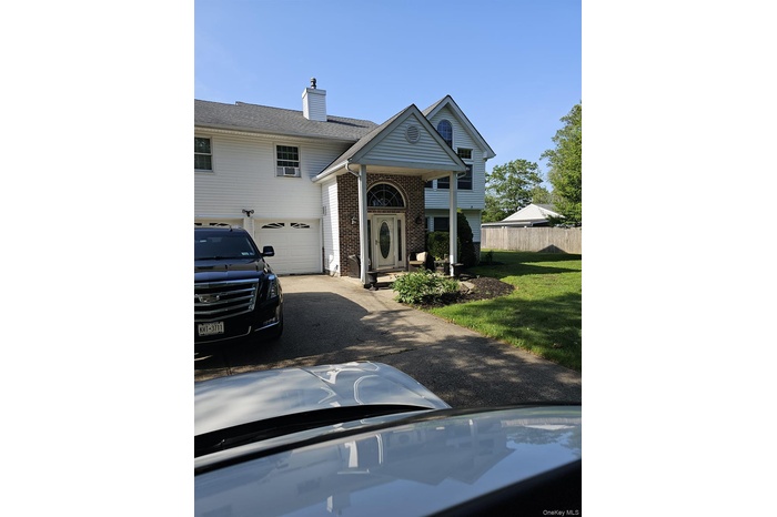 View of front facade with brick siding, asphalt driveway, and a chimney