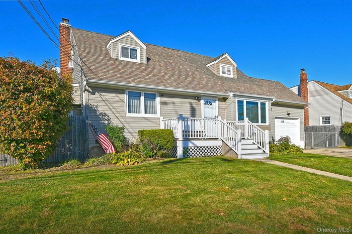 New england style home featuring a chimney, a garage, and roof with shingles