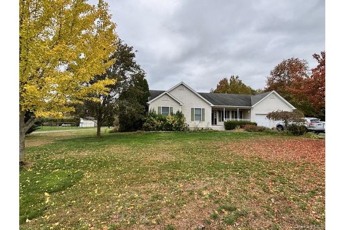 Ranch-style home with a front lawn, covered porch, and a garage
