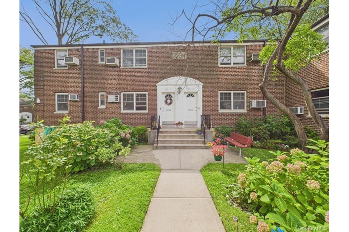 View of front of property with brick siding and a wall mounted AC