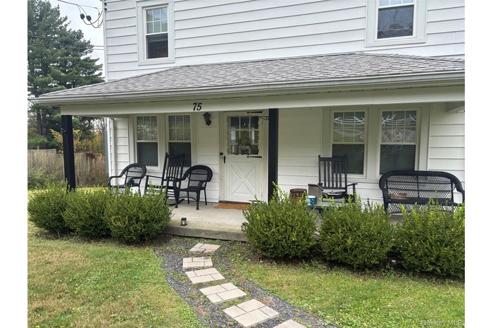 Entrance to property with roof with shingles, covered porch, and a lawn