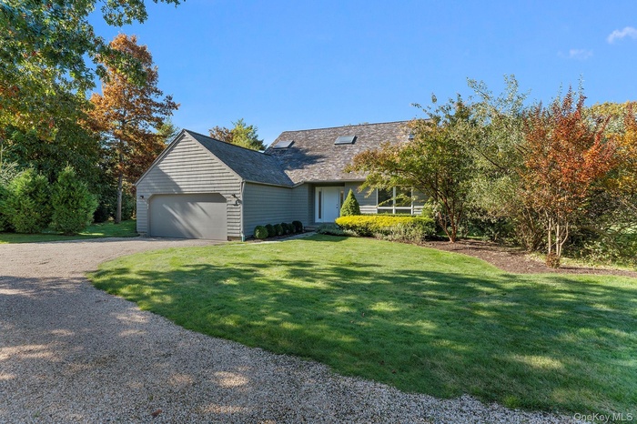 View of front of home with driveway, a front lawn, roof with shingles, and an attached garage