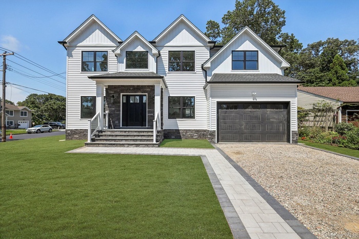 Modern inspired farmhouse featuring gravel driveway, a front lawn, a garage, covered porch, and a shingled roof