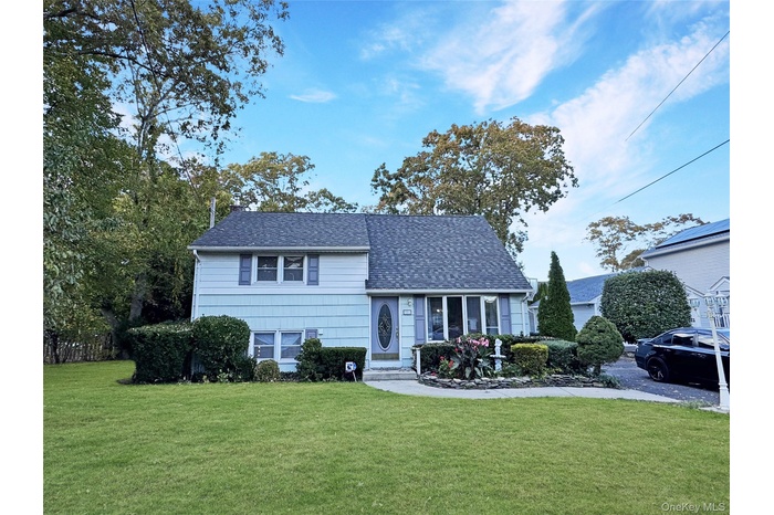 Tri-level home with a front yard and roof with shingles