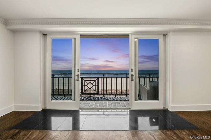 Doorway with view of water and beach and wood finished floors