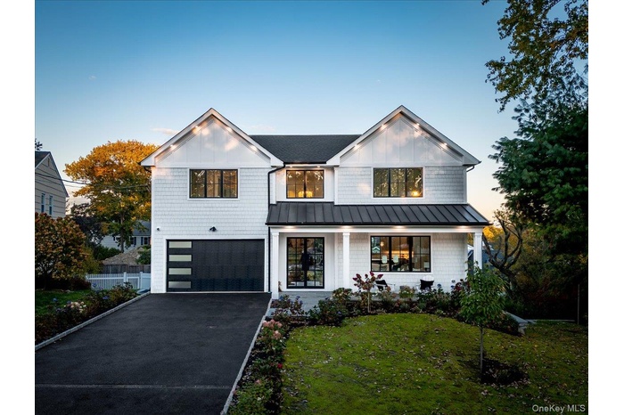 Modern farmhouse featuring a standing seam roof, a metal roof, and asphalt driveway