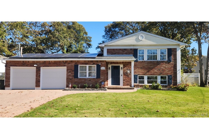 Split level home with brick siding, decorative driveway, a garage, and solar panels