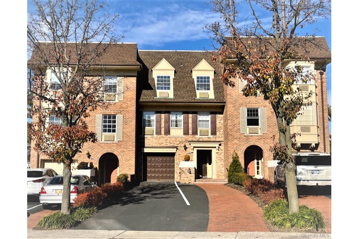 View of front facade featuring asphalt driveway, a shingled roof, and brick siding