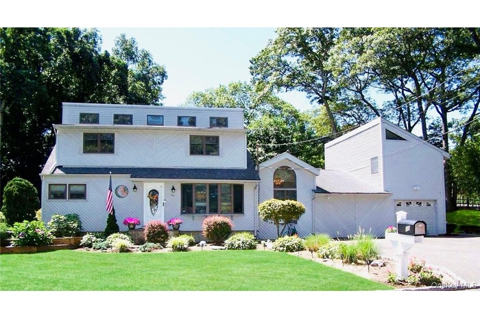 View of front of home featuring a garage, driveway, and a front lawn